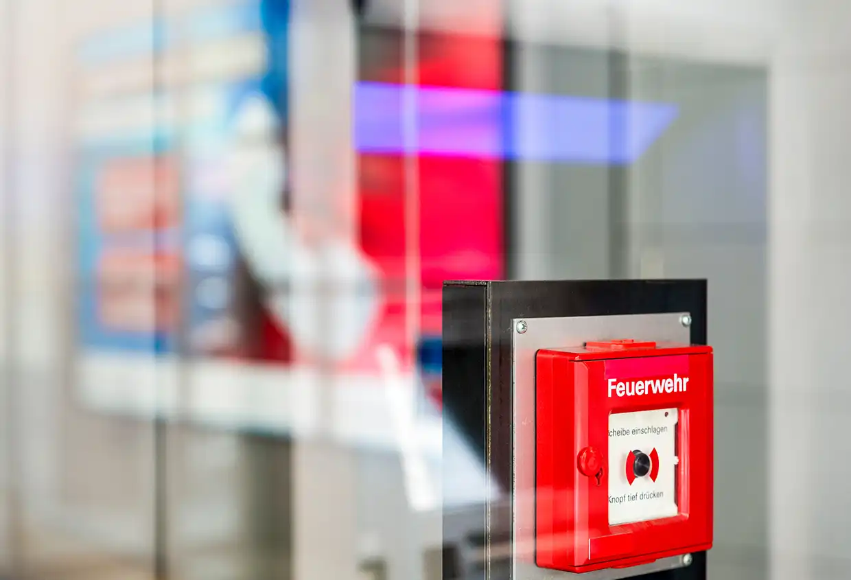 Roter Feuerwehr-Notrufmelder an einer Glasfassade
