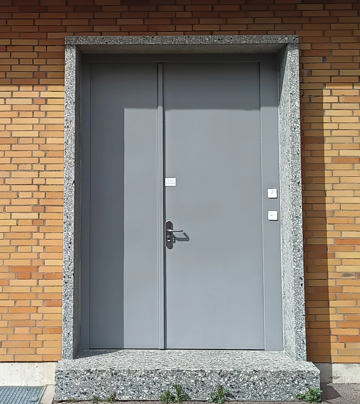 Zweiflügelige graue PLANE LINE Tür von BUCHELE in einer Klinkerfassade