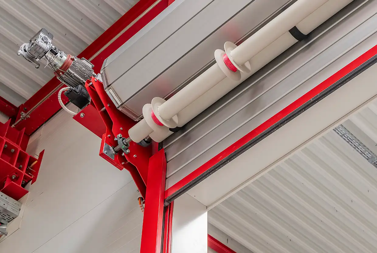 Antriebseinheit und Wickelwelle eines LM LINE Rolltors von BUCHELE mit roter Konstruktion