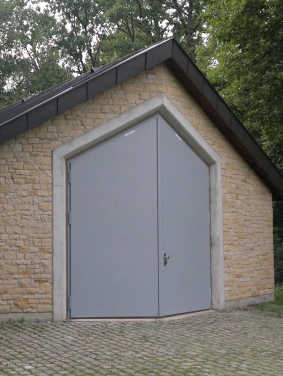 Graues zweiflügeliges Tor in einem Sandsteingebäude einer Wasserversorgungsanlage