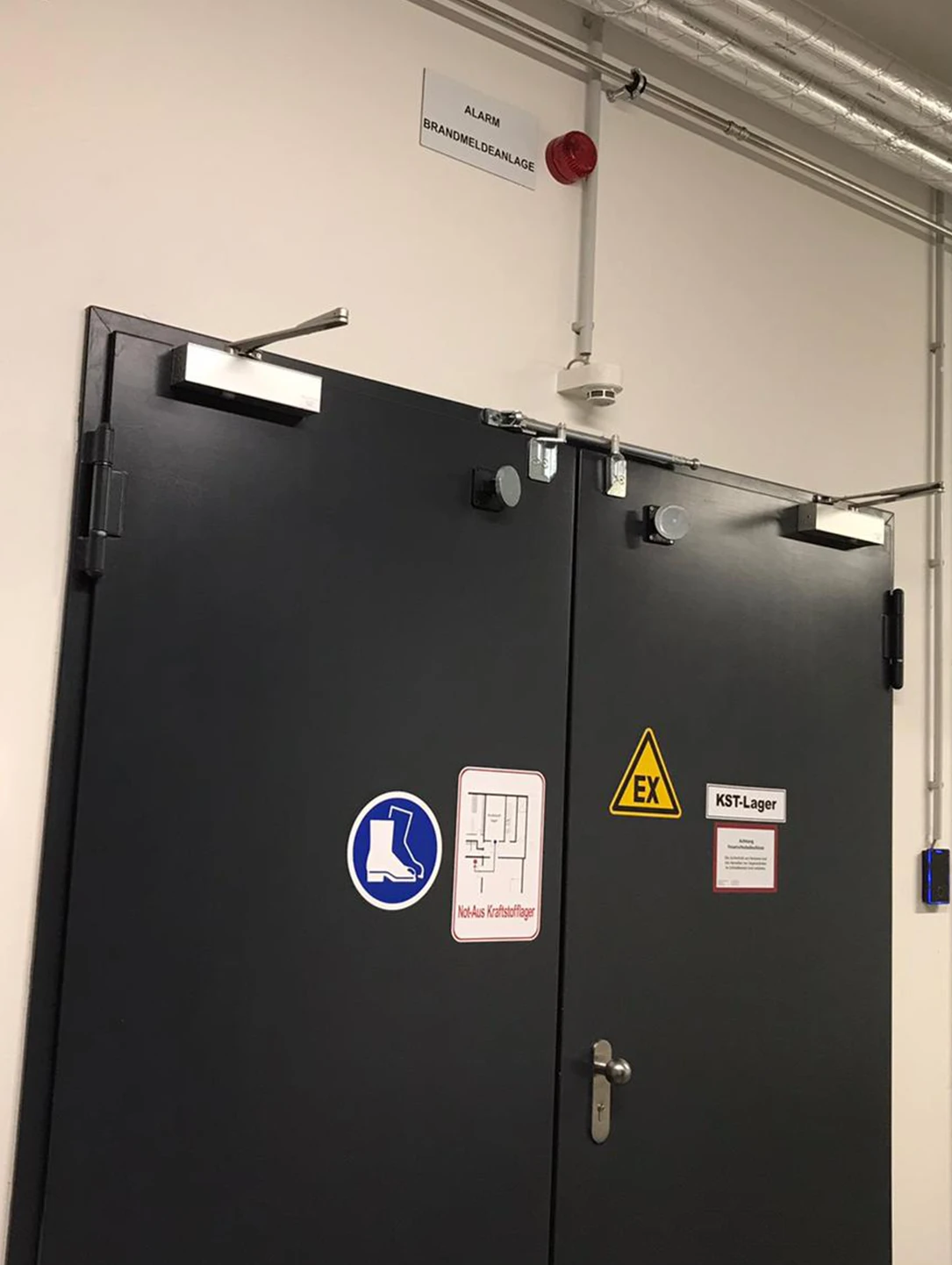 Schwarze zweiflügelige Brandschutztür mit Türschließern in einer Prüfhalle der Automobilindustrie