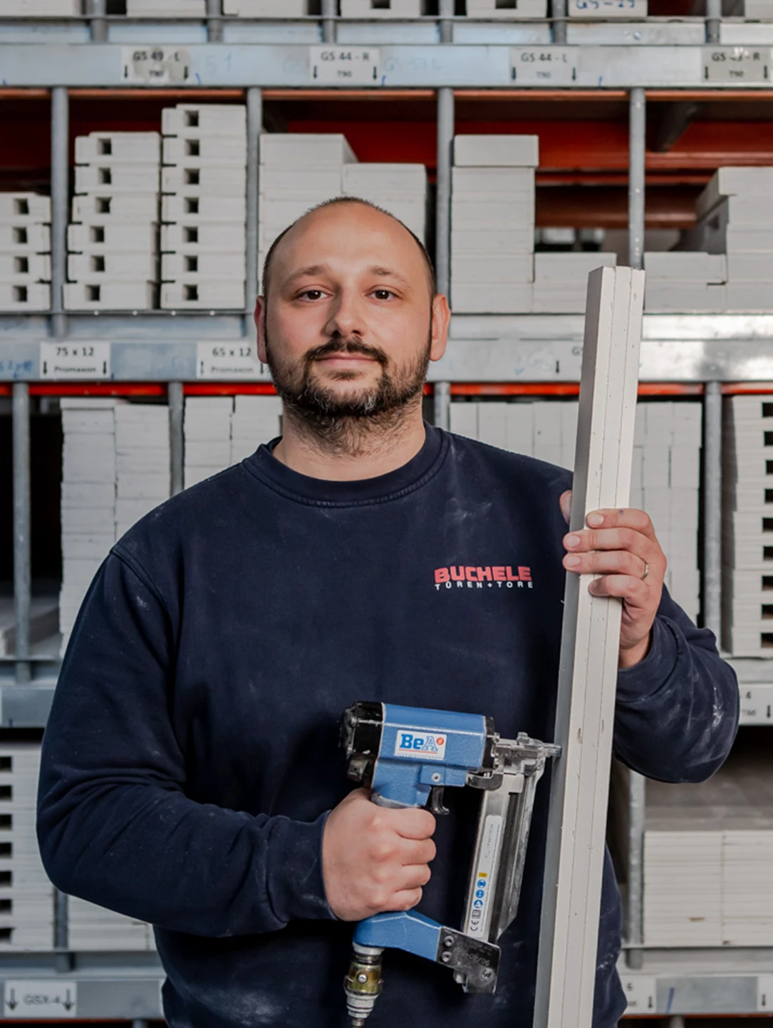 BUCHELE-Mitarbeiter mit Druckluftnagler und Profil im Lager