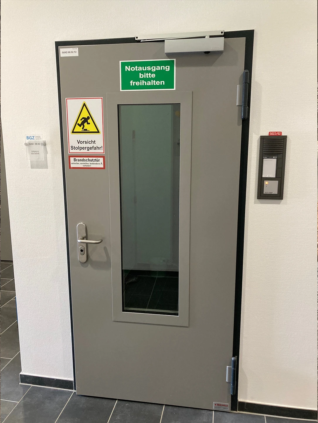 Beige Brandschutztür von BUCHELE mit Sichtfenster und Notausgang-Schild