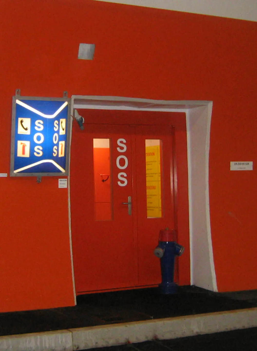 Roter SOS-Notausgang mit Glastüren in einem Straßentunnel