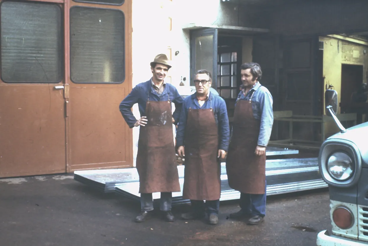 Three employees in leather aprons in front of the Buchele workshop, 1950