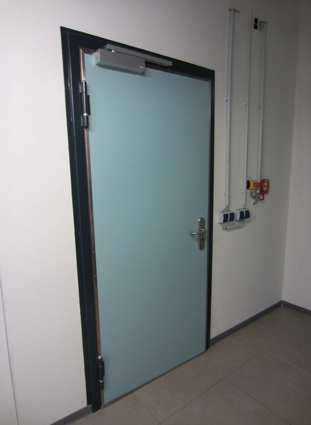 Light blue HF shielding door by BUCHELE with door closer in a laboratory corridor