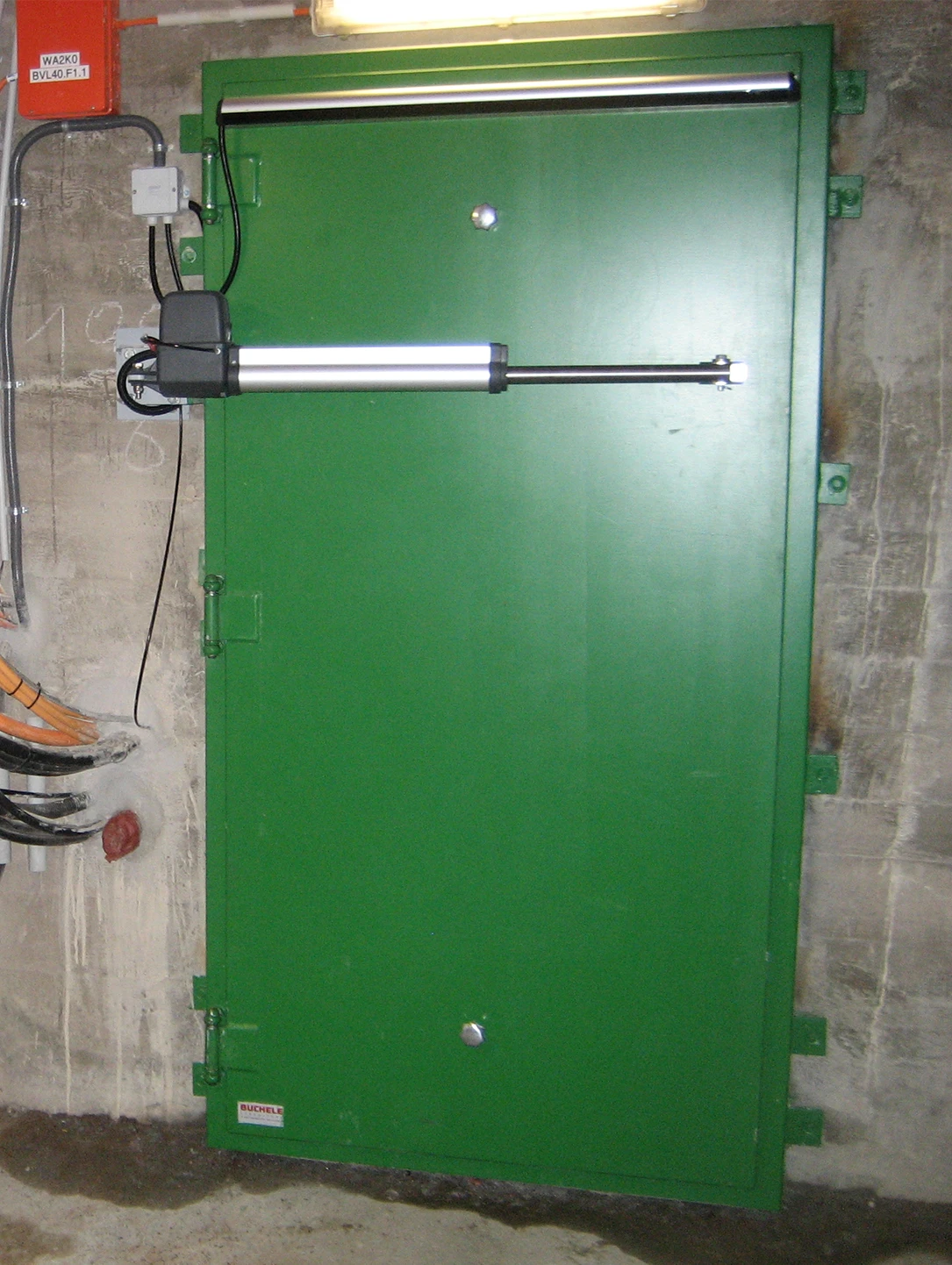 Green pressure-resistant steel door with hydraulic drive in a concrete wall