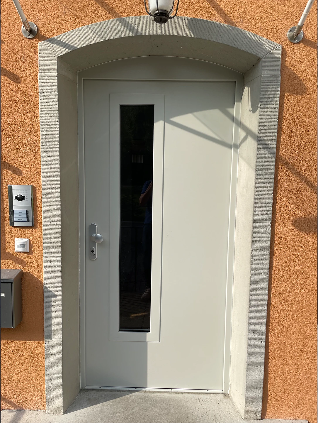 White security door with narrow glazing in a sandstone portal of a barracks