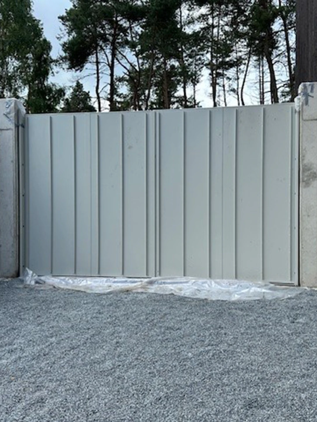Grey security gate by BUCHELE in a wall topped with barbed wire