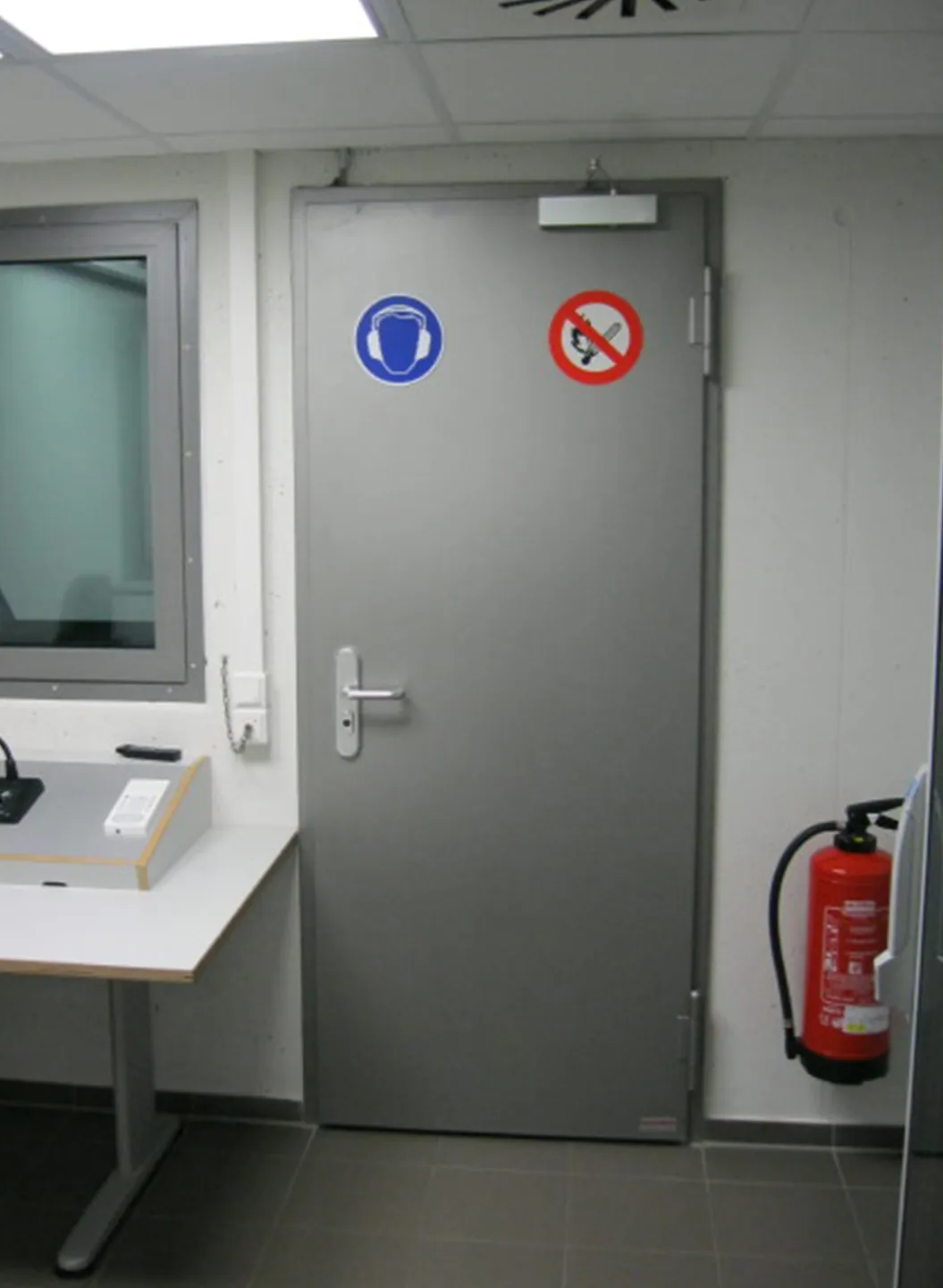 Grey sound insulation door with vision panel and signs in a test room