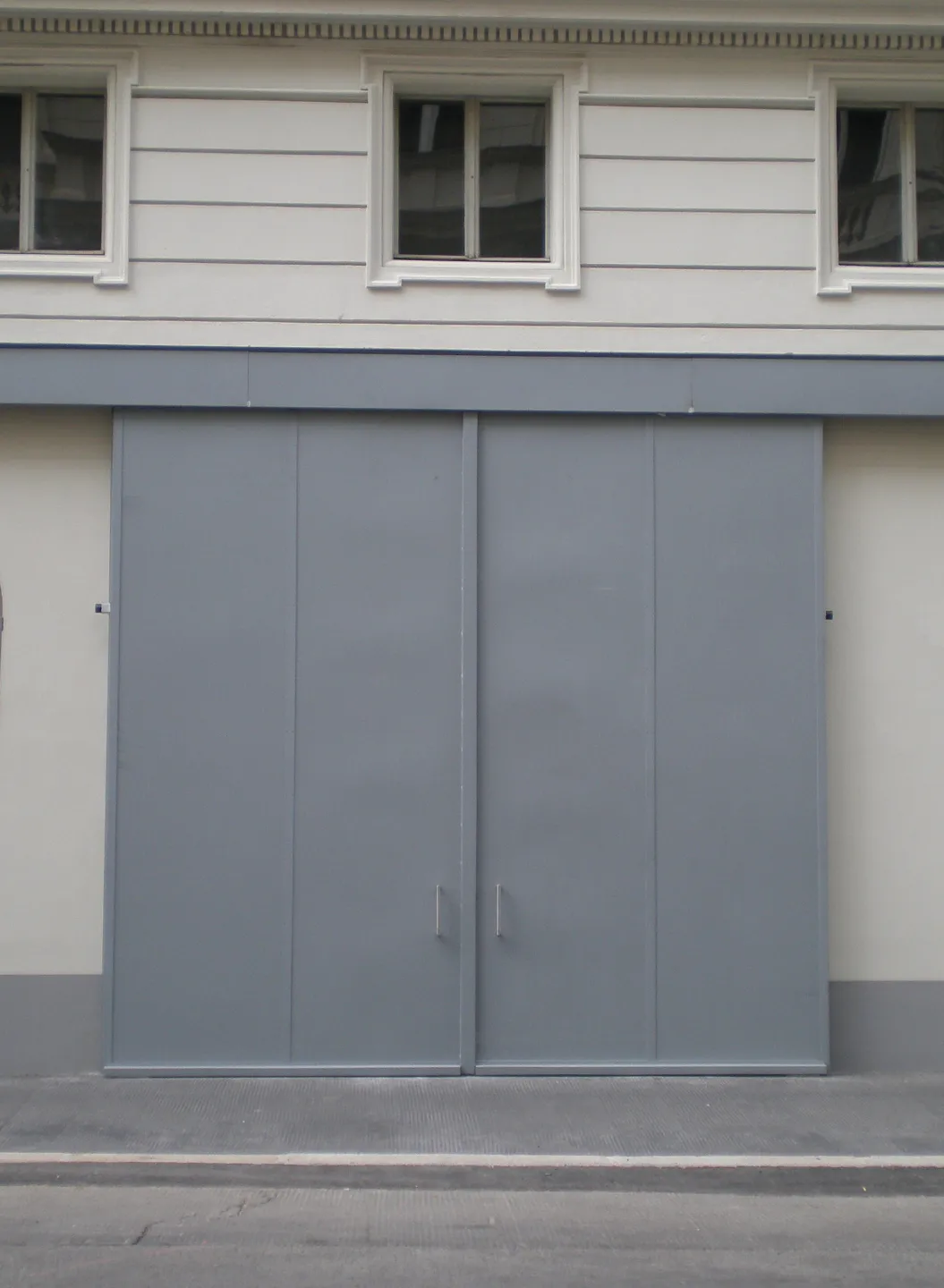 Grey sliding gate by BUCHELE at a historic building with light facade