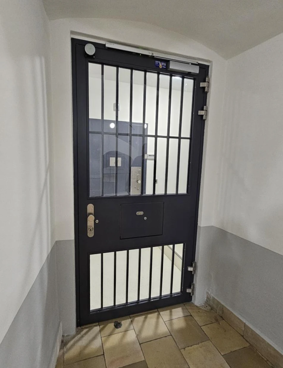 Schwarze SEC LINE Sicherheitstür von BUCHELE mit Gitterelement in einem Treppenhaus