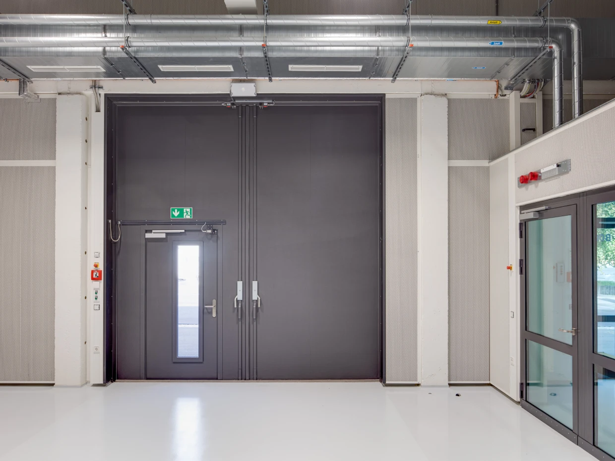 Anthrazitfarbene zweiflügelige Tür mit Fluchttür in einer Prüfhalle der TU Dresden